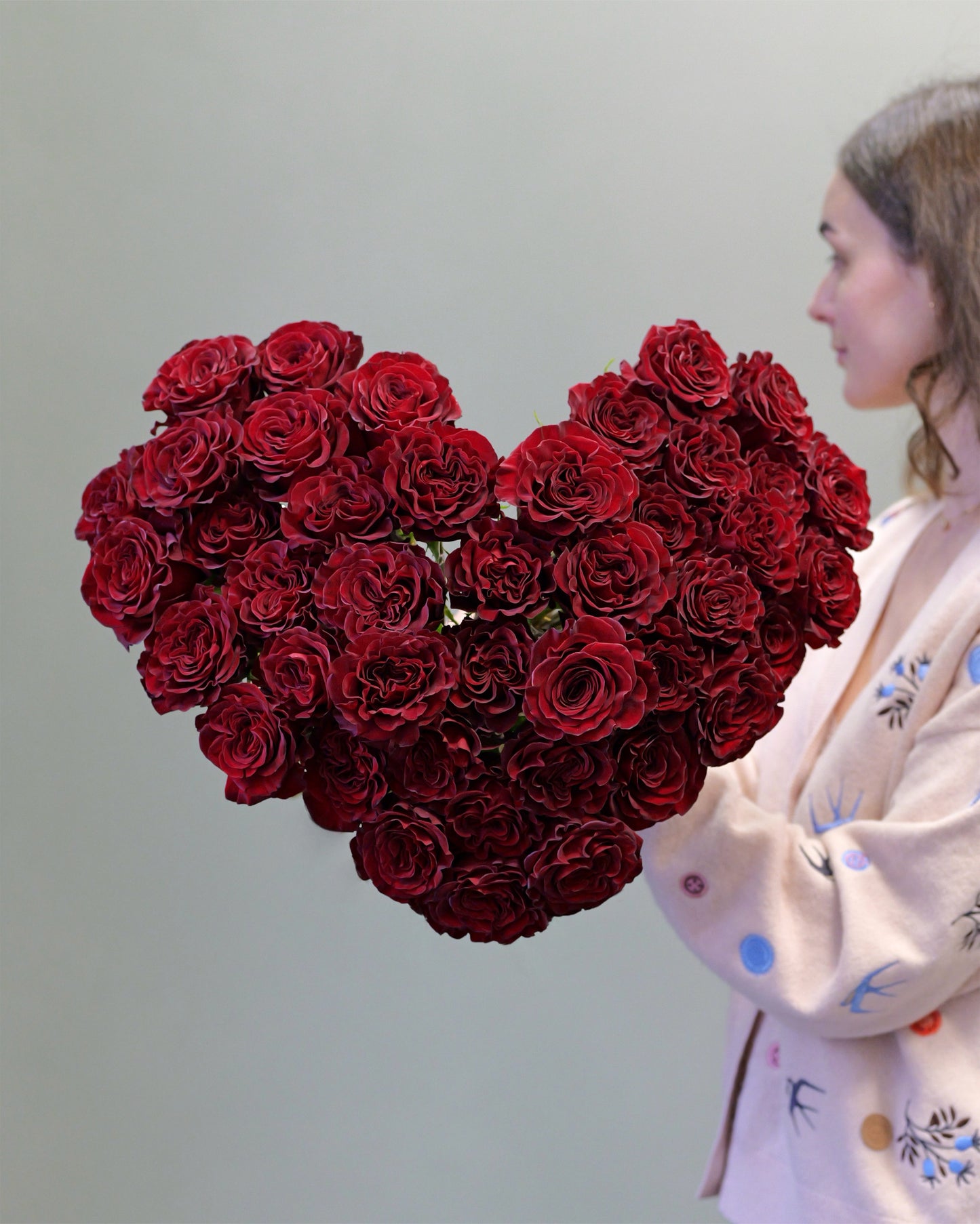 Luxusní kytice ve tvaru srdce složená z tmavě rudých růží odrůdy Hearts, detailní textura okvětních lístků, dárková kolekce ke dni svatého Valentýna.