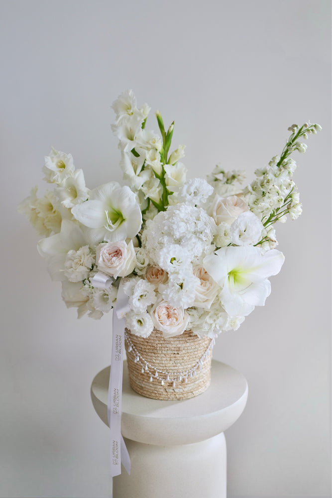 Zimní kytice Winter Queen v proutěném koši s bílými květy amarylisů, růží a hortenzií | Urban Bloom